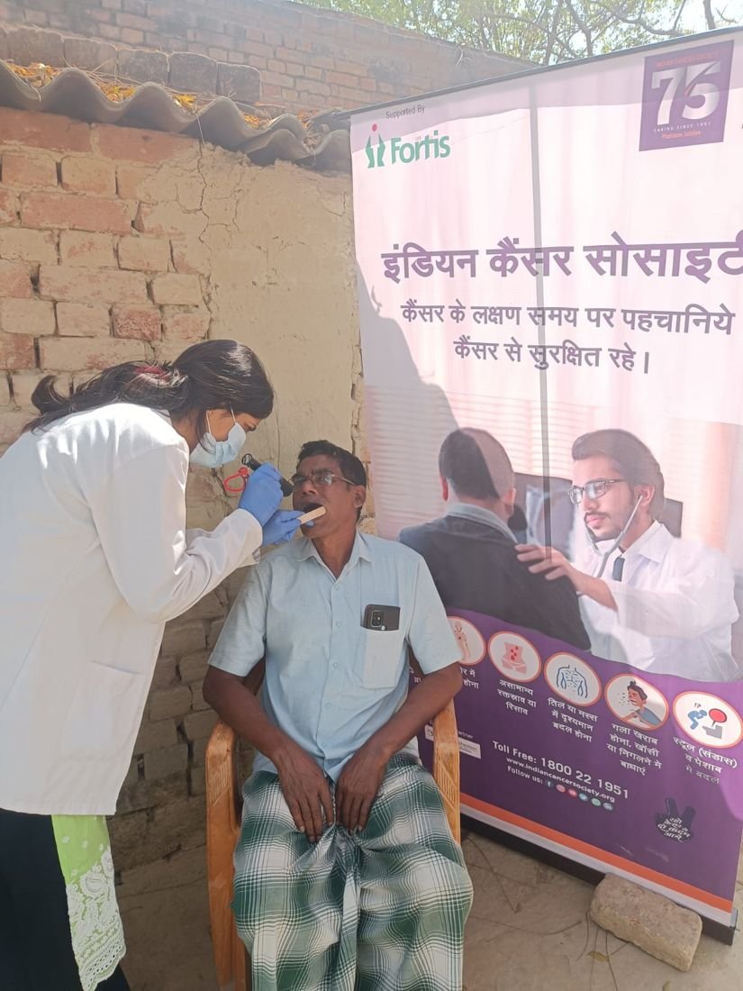 A health worker screens a man at a cancer screening camp