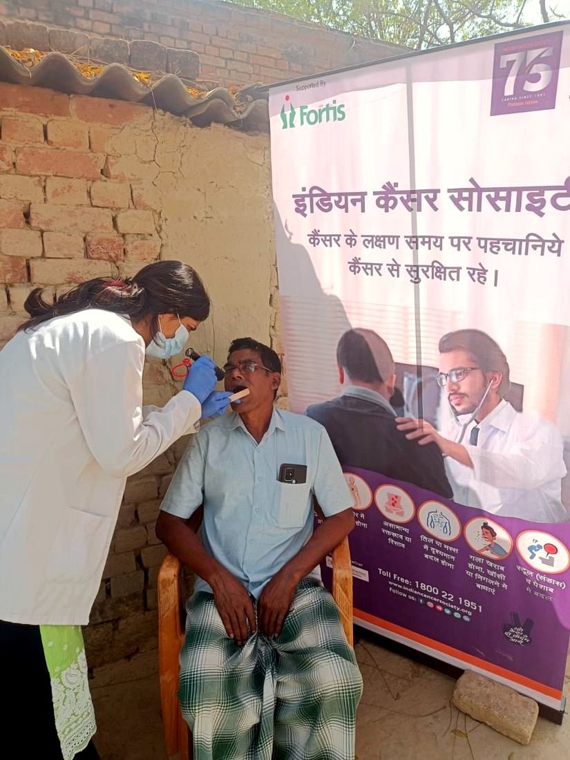 A health worker screens a man at a cancer screening camp